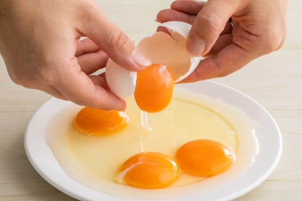 生卵をお皿に割っているところ