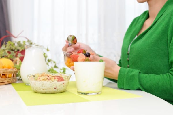 ヨーグルトやフルーツを食べようとしている女性